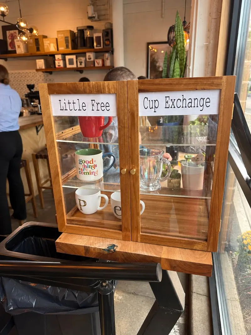 A Little Free Cup Exchange cabinet of mugs by a coffee shop window.